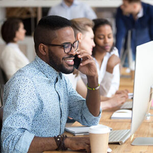 Smiling man talking on phone and computer